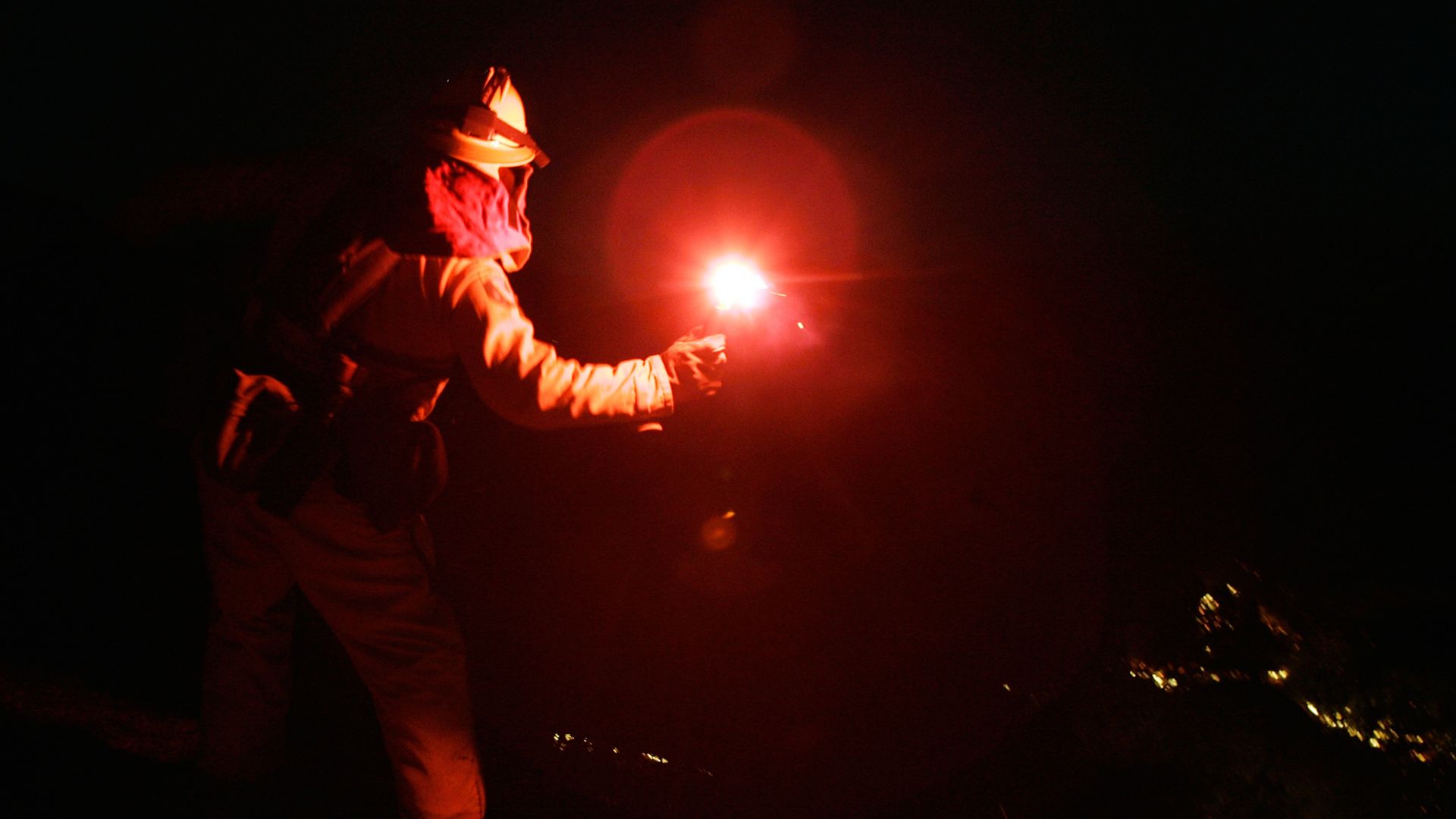 A firefighter throwing a flare. 