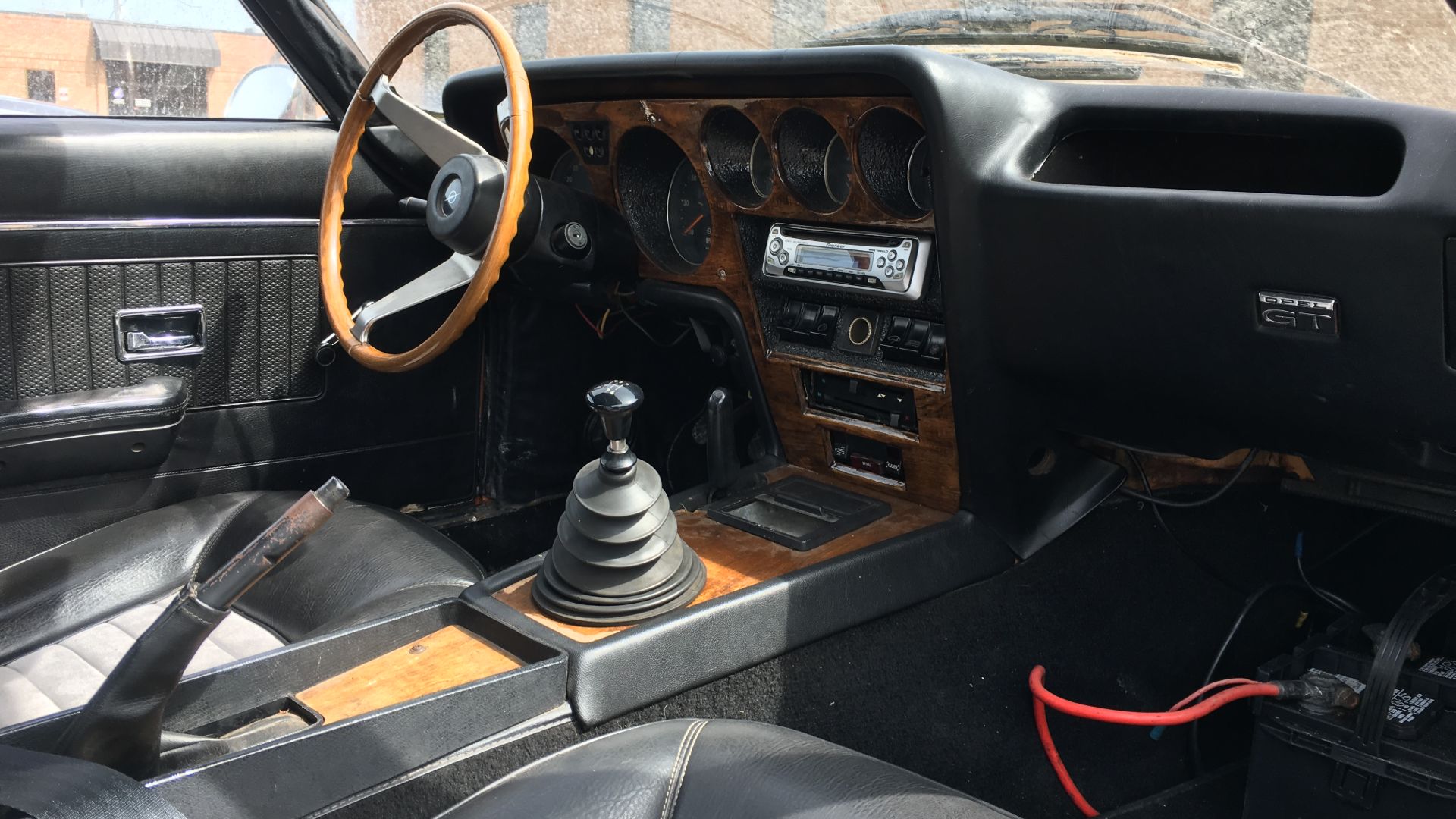 The interior of an Opel GT with wood trim and black leather.