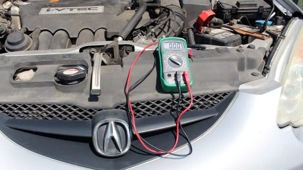 A multimeter on the front part of an Acura RSX engine bay.