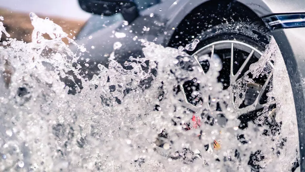 A close-up of a Porsche wheel going through water.