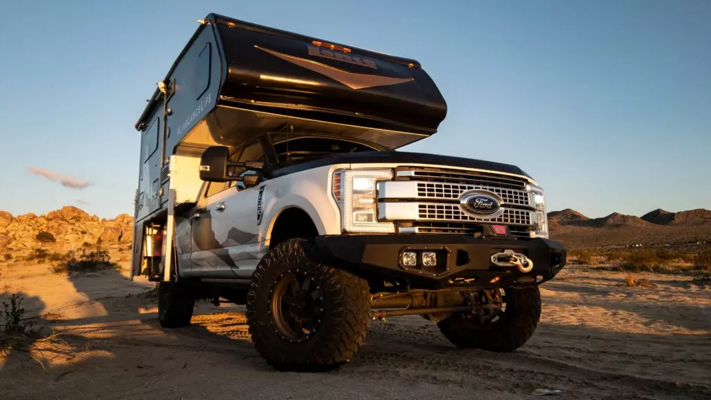 A truck camper on top of a massive Ford Super Duty.
