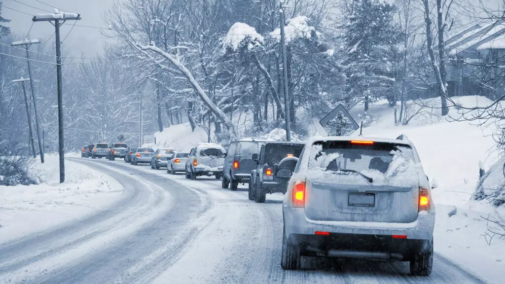 A line of cars driving on a snow-covered road.