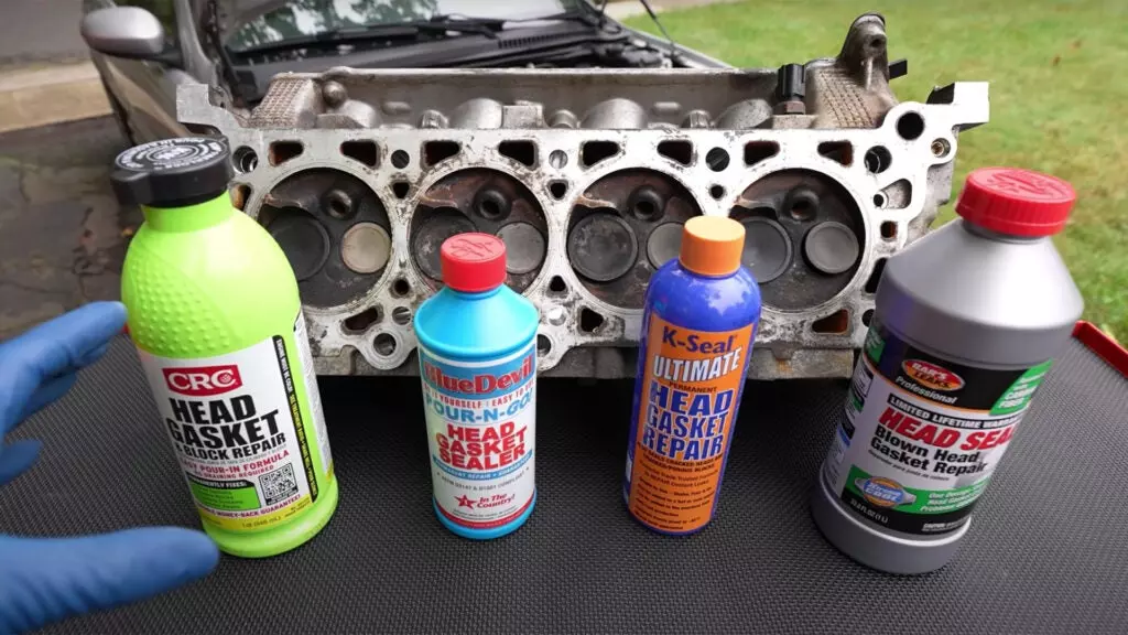 Four types of head gasket sealers in front of an engine.