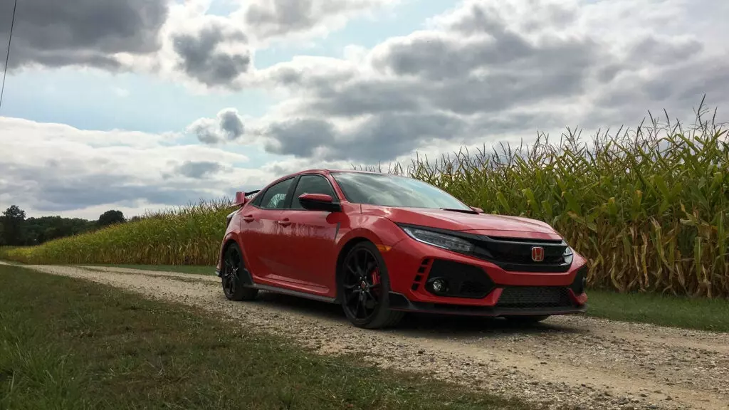 The passenger front three-quarter view of a red Honda Civic Type R in a cornfield.