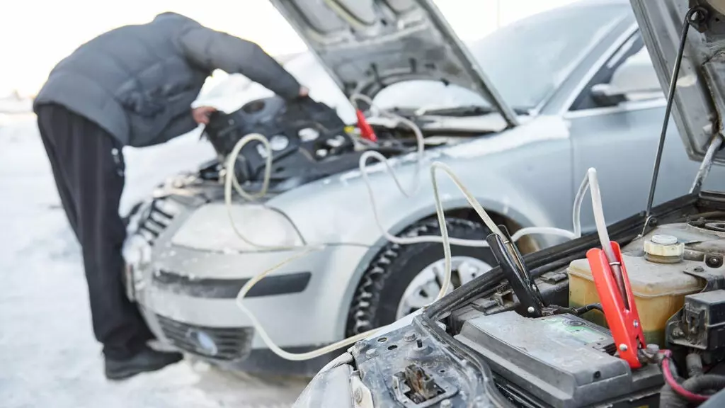 A person jump-starting a car.