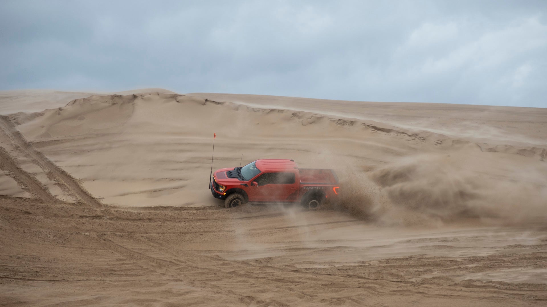 2023 Ford F-150 Raptor R doing a wall ride on a sand dune.