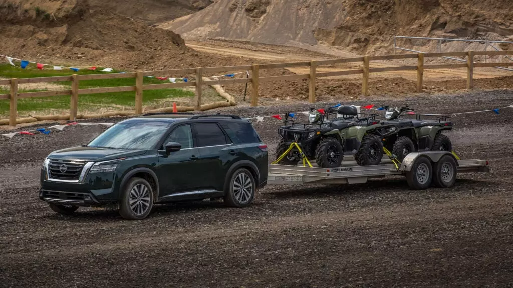 A Nissan Pathfinder tows two four wheelers.